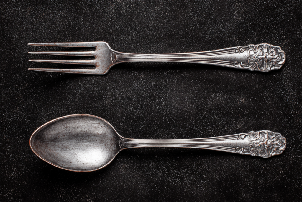 Une fourchette et une cuillère posées sur la table, sur fond noir, vues de dessus, couverts en argent