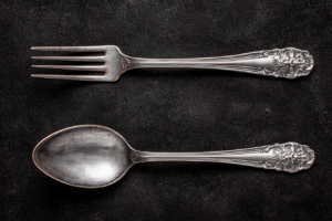 Une fourchette et une cuillère posées sur la table, sur fond noir, vues de dessus, couverts en argent