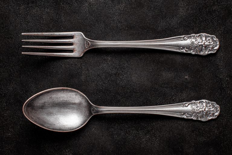 Une fourchette et une cuillère posées sur la table, sur fond noir, vues de dessus, couverts en argent